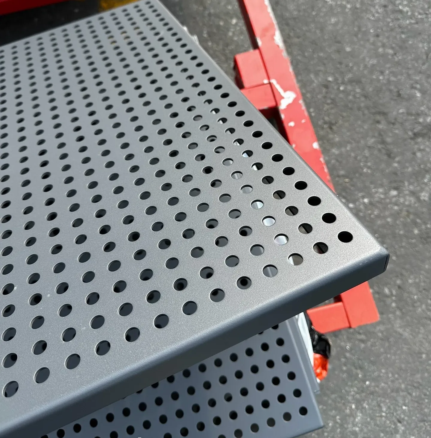 Close view of dark perforated panel with folded perimeter edge